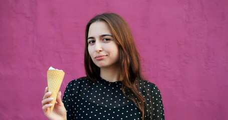 Young woman closing eyes while holding ice cream cone before pink backdrop, sweet vanilla drip catching light, concept cinematic shot emphasizing cone texture and serene indulgence mood.