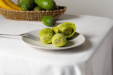 Peeled prickly pears ready to be eaten with fork on white tablecloth