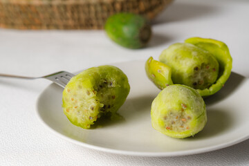 Peeled prickly pears ready to be eaten with fork on white plate