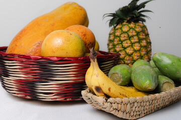 Baskets overflowing with fresh tropical fruits: papaya, mango, pineapple, bananas, and prickly pear