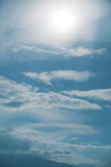 Fototapeta premium Bright blue sky with white clouds and glowing sun for background, texture, nature and design concepts, 눈부신 태양과 흰 구름의 파란 하늘 배경, 텍스처, 자연, 디자인 콘셉트 활용