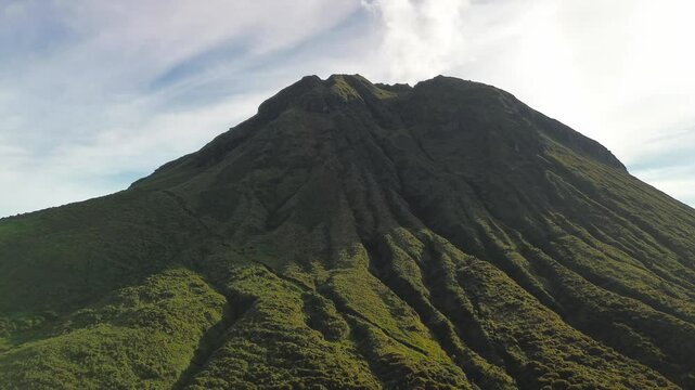 Low-level flyby along Mount Apo&rsquo;s green volcanic flanks reveals deep erosional ribs and a faint steam plume curling into a pastel morning sky.
