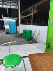 Nighttime scene of a food stall with seating area and trash cans.