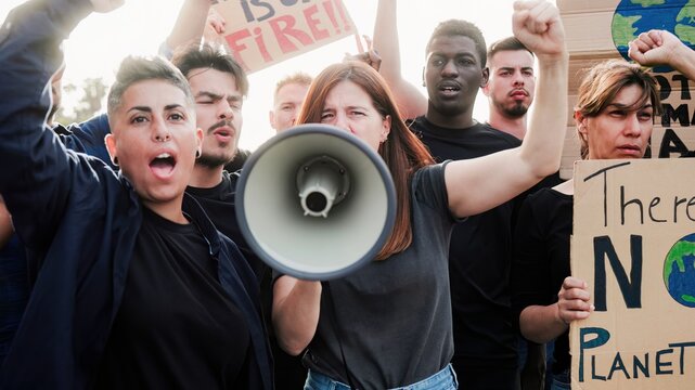Multiracial climate change protest in city with serious hispanic woman using megaphone and signs raised