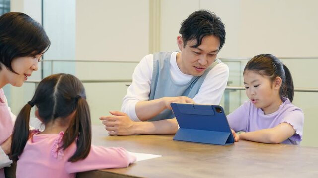 タブレットを見る女の子と使い方を教える男性