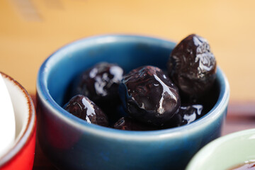 Dark olives in a blue bowl on a wooden table