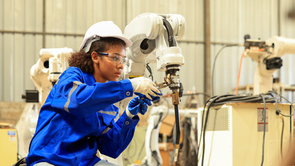 African american engineer woman fixing and testing an Artificial Intelligent welding robotic...
