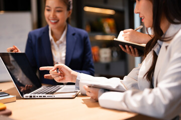 Confident youg businesswoman teaching interns or helping new employees in the organization, using...