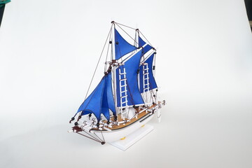 Miniature of a Traditional sailing boat made from wood and has blue sail
