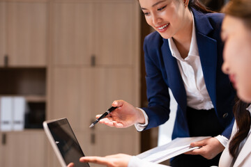 Confident youg businesswoman teaching interns or helping new employees in the organization, using...