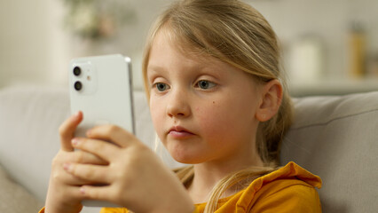 Little European girl holding mobile phone smartphone cellphone surprised wow shocked unexpected emotional amaze victory technology gadget web network excited child kid pupil daughter delight astonish