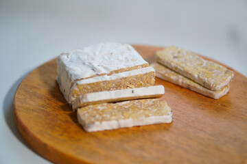 Tempeh that has been cut into pieces on a wooden cutting board
