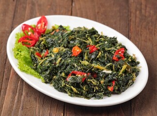 Tumis Daun Pepaya. Sauteed papaya leaves are papaya leaves sautéed with garlic, shallots and red chilies