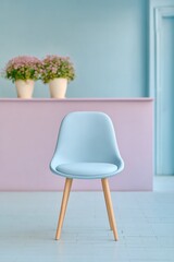 Modern healthcare clinic waiting area with pastel blue chair, light wood legs, pink reception desk, and potted plants for welcoming patient comfort environment
