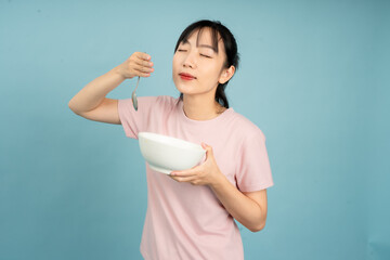 Person enjoys a delicious meal while standing against a light blue background in a casual indoor...