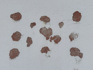 Peeling red paint on white textured wall with visible cracks