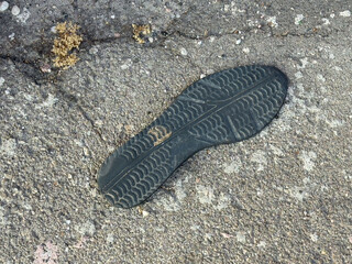 Embedded shoe sole on cracked pavement with textured surface details