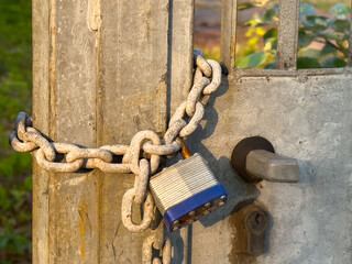 Rusty chain and padlock securing metal gate in sunlight