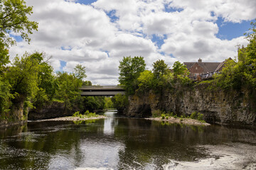 Fergus - town in Ontario on the Grand River, popular tourist town with beautiful old stone houses, a waterfall, and ancient bridges. A tourist magnet. Summer sunny day with cloudy sky. Ontario, Canada