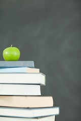 Green apple in front of blackboard on books