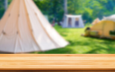 Empty wooden table on blurred background of camping tents in campground area at nature park for montage mockup product display in relaxing activity and recreation on natural traveling concept