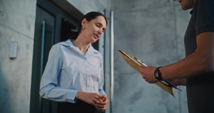 Postman Delivering Small Parcel for Recipient in Modern Office, Getting Client's Signature. Businesswoman Taking Padded Envelope with Online Shopping Order. Delivery or Postal Service. Slow Motion.