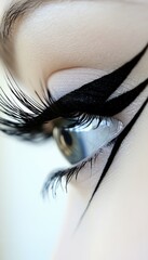 Extreme close-up of a blue eye, showcasing bold, artistic black eye makeup and long lashes, creating a striking, stylish visual.
