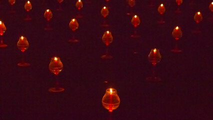 A large number of candles are lit at borobudur temple. The candles are arranged in a pattern, with some candles grouped together and others spaced apart. Scene is one of warmth and coziness