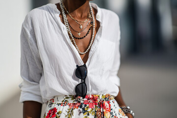 Close-up detail: black sunglasses, layered necklaces, white cotton shirt, floral maxi skirt, 