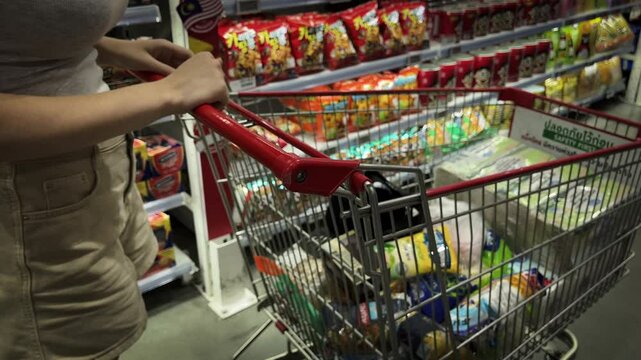 cart with food and in the supermarket. girl chooses goods for purchase.