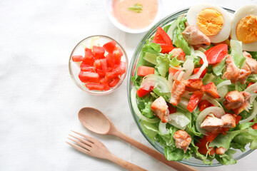 A cesar salad bowl filled with lettuce, tomatoes, egg and chicken. The salad is served in a clear glass bowl