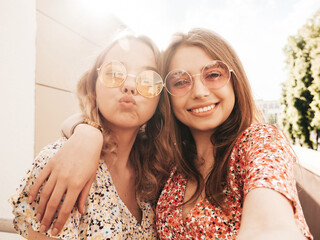 Two young beautiful smiling hipster female in trendy summer sundress.Sexy carefree women posing on...