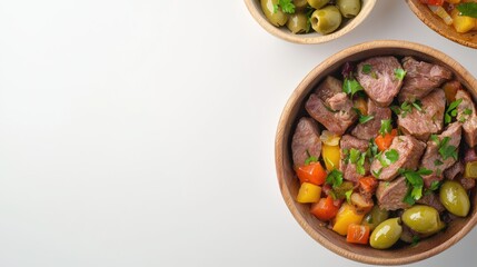 Delicious beef cubes mixed with olives and colorful vegetables, seasoned with fresh parsley, are presented in a wooden bowl against a clean white background.