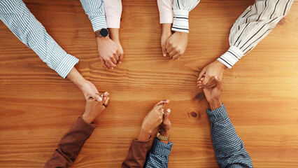 Holding hands, collaboration and business people by table in office for synergy, unity or support....