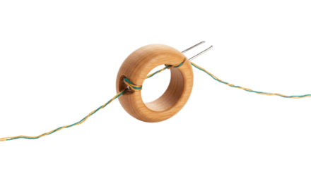 Wooden ring with threaded needle and green yellow string isolated on white