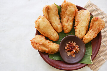fried bananas or pisang goreng served on a plate with banana leaf. The plate is on a wooden table