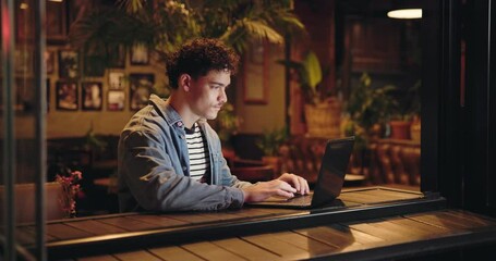 Coffee shop, remote work and man typing on laptop to research story or review email for journalism. Computer, online or freelancer in cafe for news article, editing headline or fact checking at night - Powered by Adobe