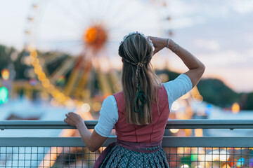 Back view of a woman in Bavarian costume standing among the crowd at a traditional festival in...