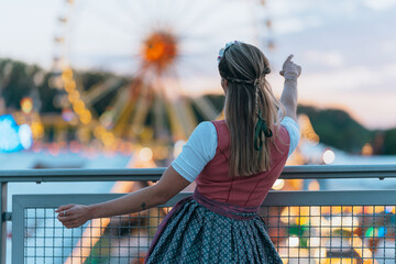 Traditional Bavarian woman seen from behind as she admires the festive scene at a German folk event...
