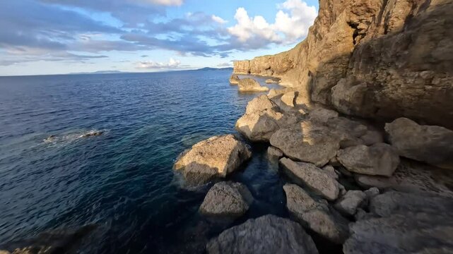 Bird's eye view of flying above beautiful sea and cliff in Okinawa at the sunset