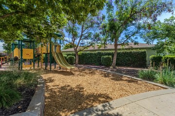 Sunny playground with slides and trees.