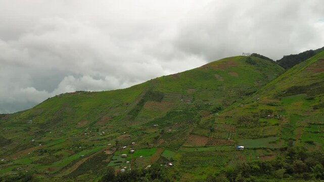Mount Apo&rsquo;s foothills unfold as a vivid quilt of vegetable plots and scattered huts, their green-brown terraces fading into low, drifting cloud banks along the horizon.