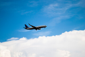 A passenger plane flies in the sky above white clouds. Air travel