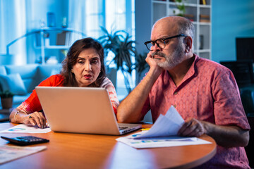 Elderly couple using laptop to manage pension planning, bills, and household finance at home