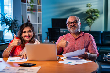 Elderly couple using laptop to manage pension planning, bills, and household finance at home