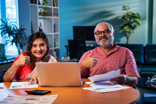 Elderly couple using laptop to manage pension planning, bills, and household finance at home - Powered by Adobe