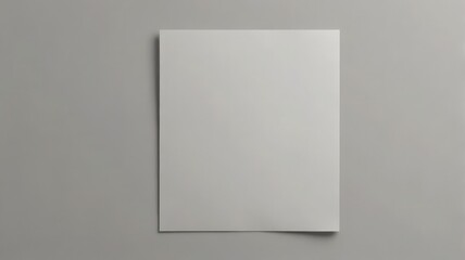Fototapeta premium A blank, white sheet of paper is placed on a solid gray background, ready for text or graphics.