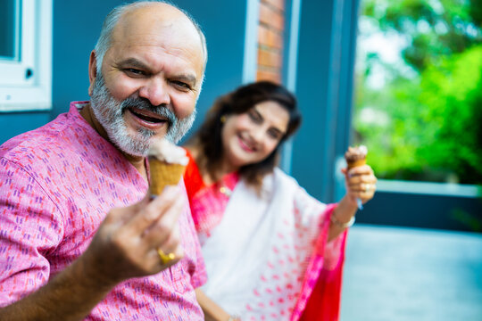 Asian elderly couple happily enjoying ice cream together outside on a warm sunny day