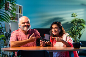 Indian senior couple using BP monitor at home, pleased with normal blood pressure reading