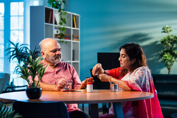 Elderly Indian couple taking medicine and managing health with daily medication and care routine